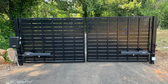 Black steel dual swing automatic driveway gate with gate operators, installed by Leon's Automatic Gates
