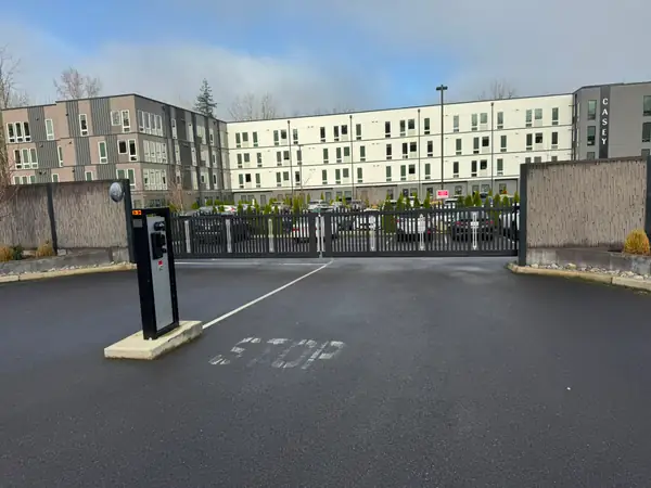 Black bi-parting slide gate with barrier arm at Casey apartment complex