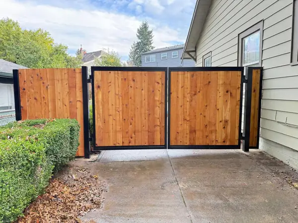 Cedar double swing driveway gate with fence wings in residential driveway