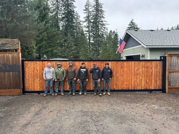 Installation crew standing in front of a finished cedar sliding driveway gate