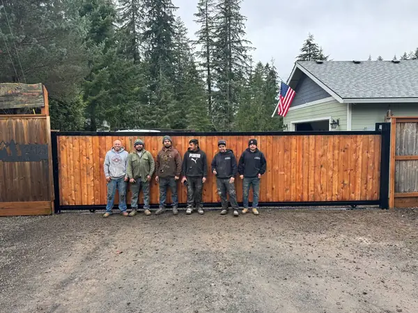 Installation crew standing proudly in front of a newly completed cedar sliding driveway gate